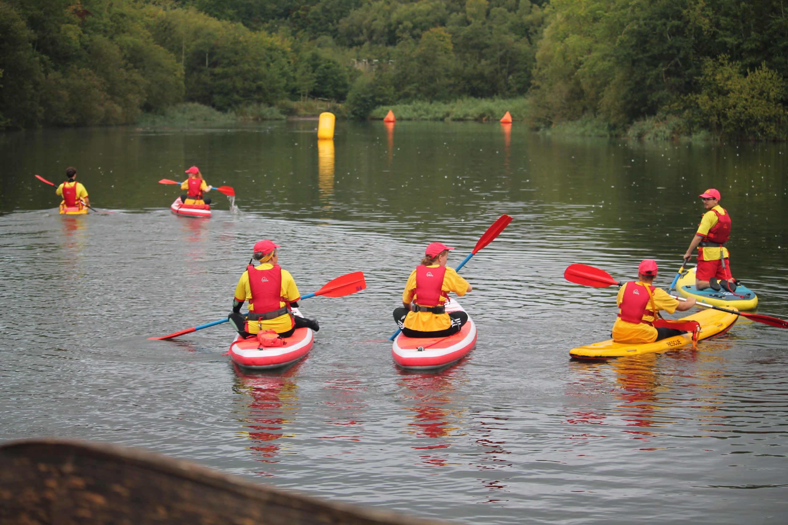 A group of lifeguards paddling to the middle of a lake.